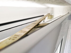 Detaillierte Nahaufnahme einer Schließ- und Kippvorrichtung in metallischer Ausführung, montiert an einem Fensterrahmen, unter Einsatzbedingungen.