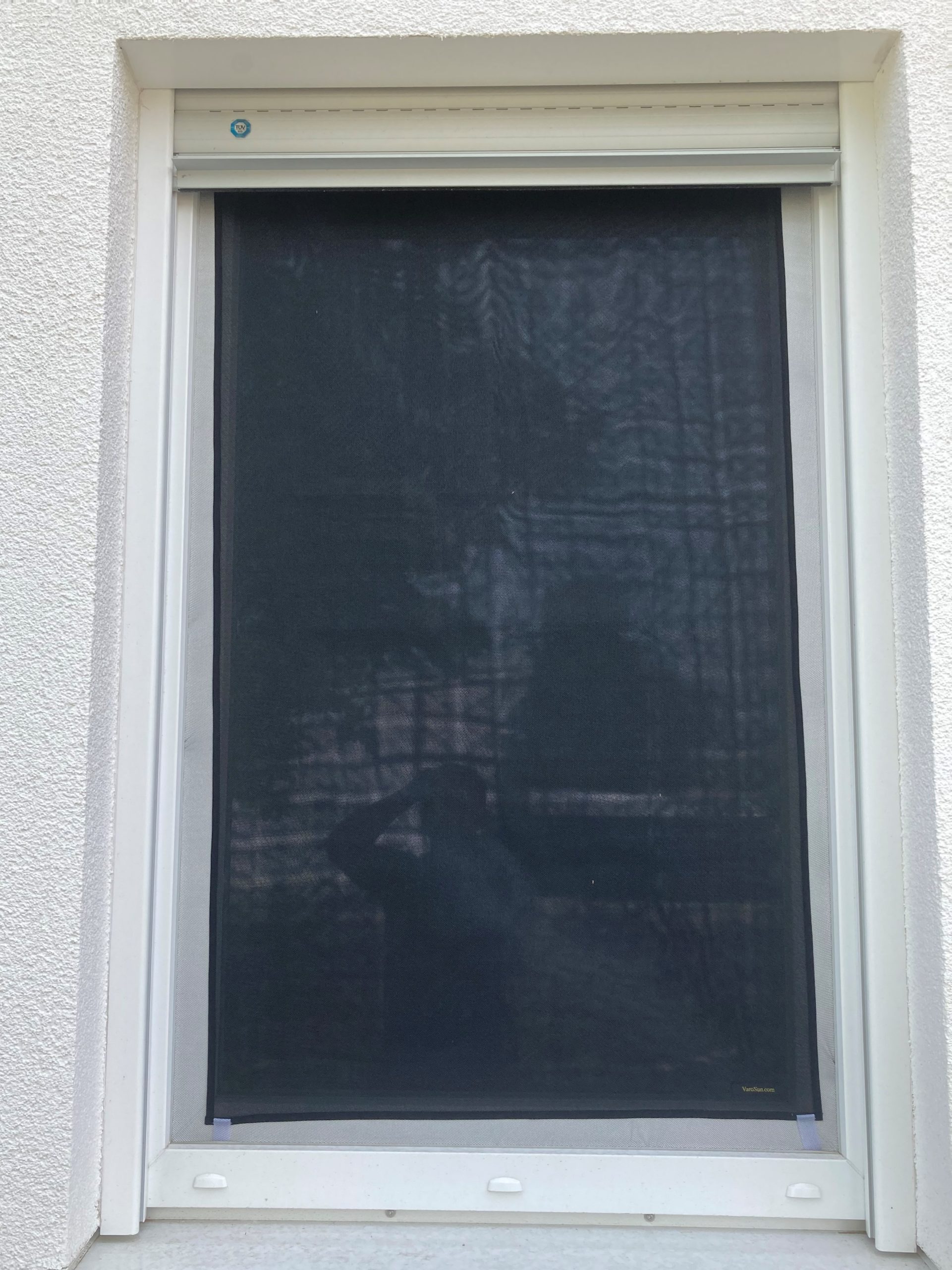 Fenster mit dunkelgrauem Gewebe-Sonnenschutz außen montiert an weißem Rahmen